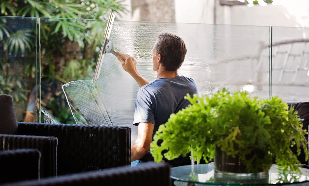 Professional cleaning a large glass window from outside